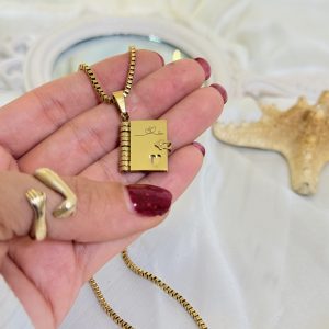 پلاک دفترچه‌ای طلایی از جنس استیل، با طراحی صفحه‌دار و زنجیر ونیزی طلایی رنگ، دارای حک ظریف روی جلد پلاک.